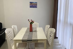 Un tavolo da pranzo con sei sedie, un vaso con fiori e un quadro appeso al muro.