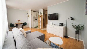 Un salon moderne avec un canapé gris, une table basse blanche et un téléviseur à écran plat fixé au mur.