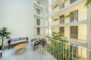 A multi-level atrium with a seating area, balconies with plants, and a view of the greenery below. - SHIN Patara Living Hotel (Bangkok)