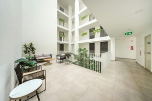 Ein mehrgeschossiges Atrium mit Sitzgelegenheiten, Pflanzen und einer Treppe.
