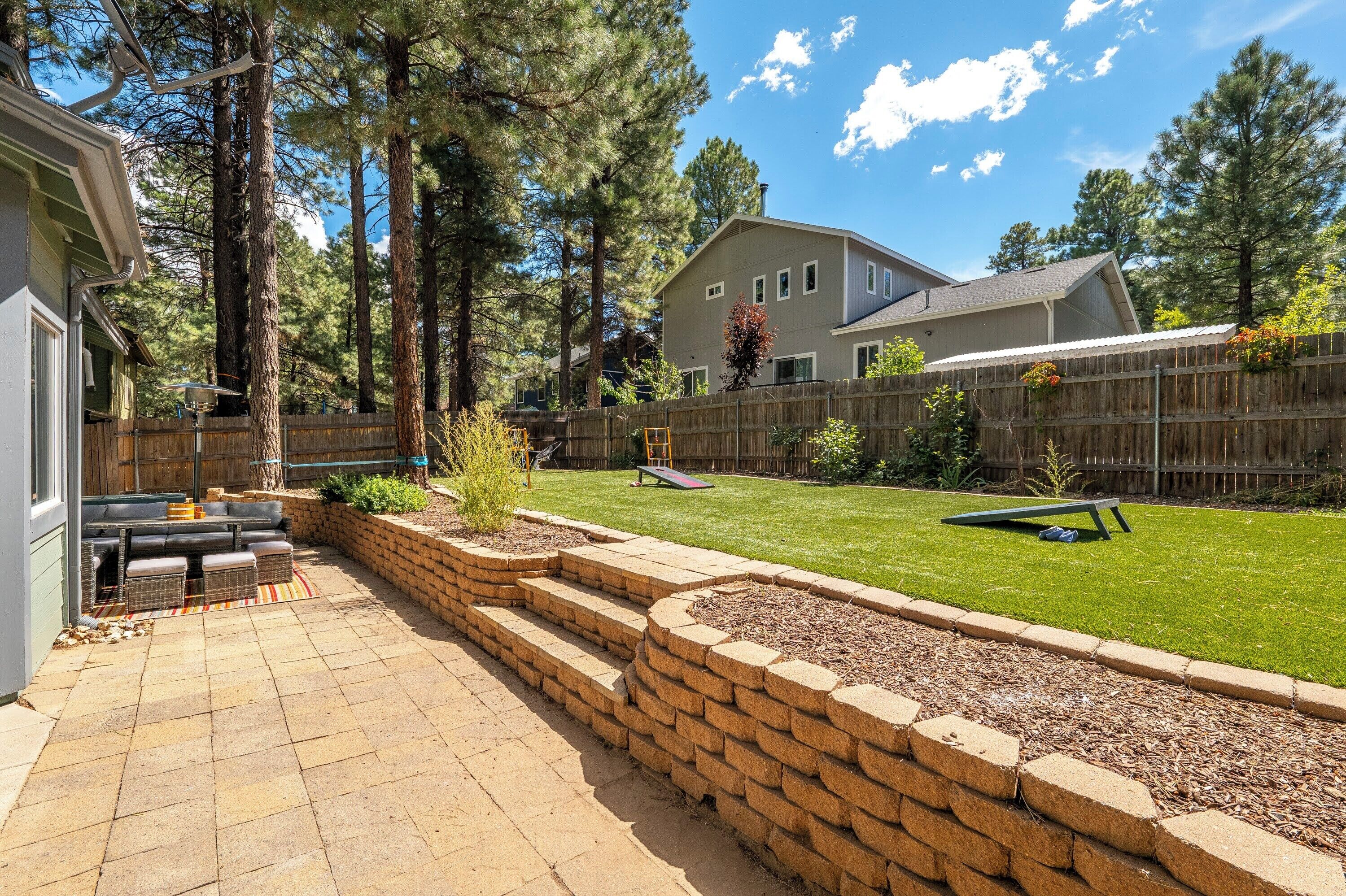 Fenced-in backyard includes a grill, firepit, lawn games like cornhole