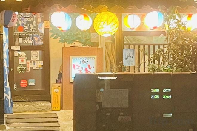 A hotel entrance with a reception desk, a poster, and a security gate.