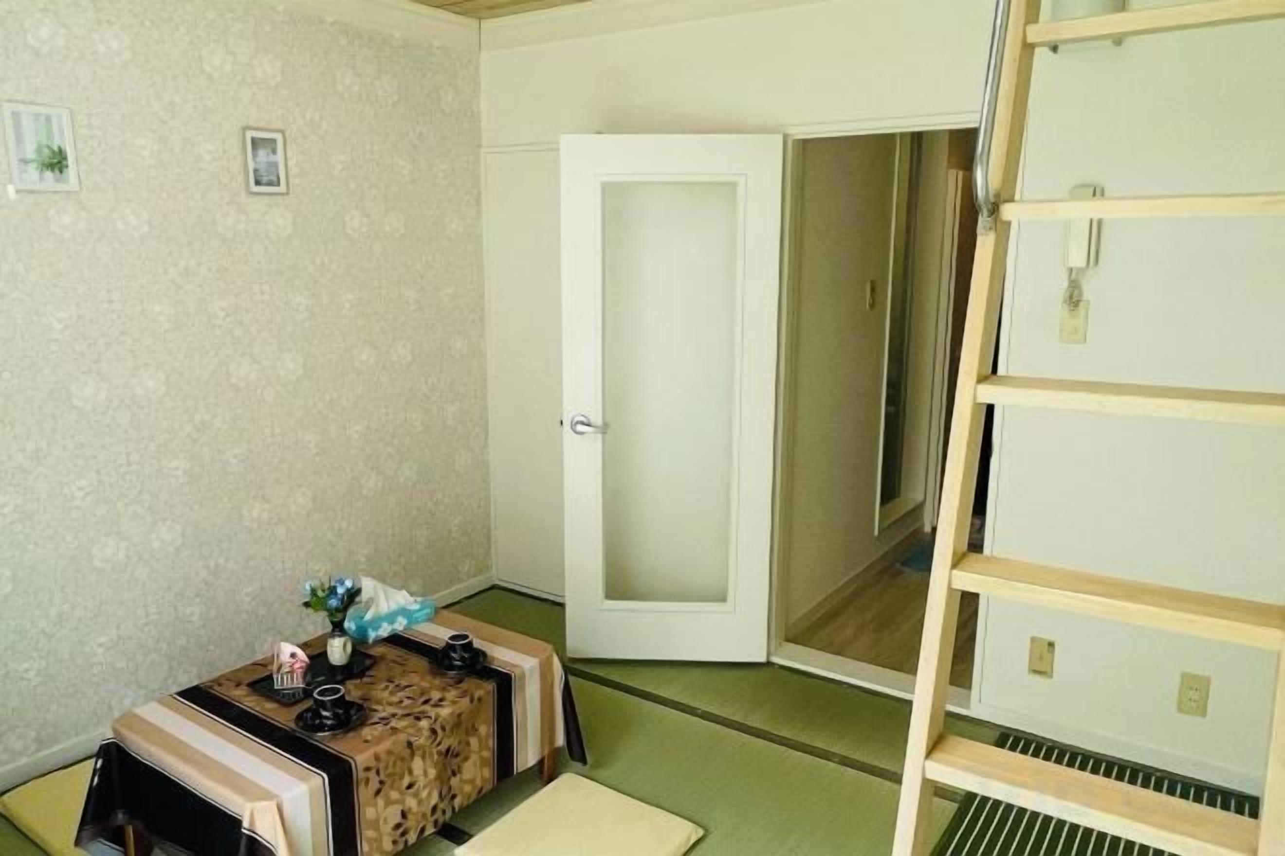 A room with a tatami mat, a small table with a vase, a door, and a sliding door.