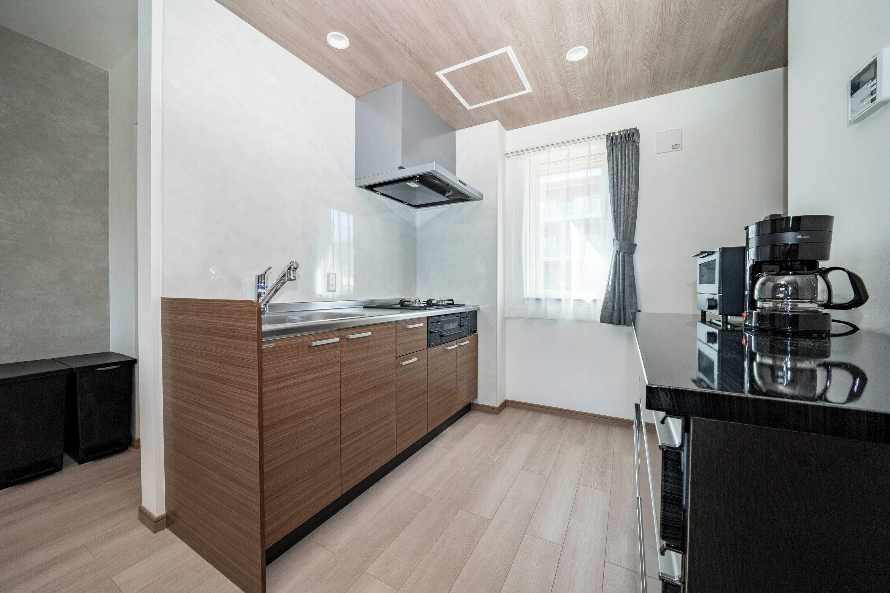 Una cocina moderna con armarios de madera, estufa integrada y cafetera.