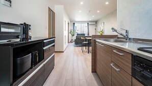 Eine moderne Küche mit integrierten Geräten, ein Essbereich mit einer Couch und einem Tisch sowie Blick zum Wohnzimmer.