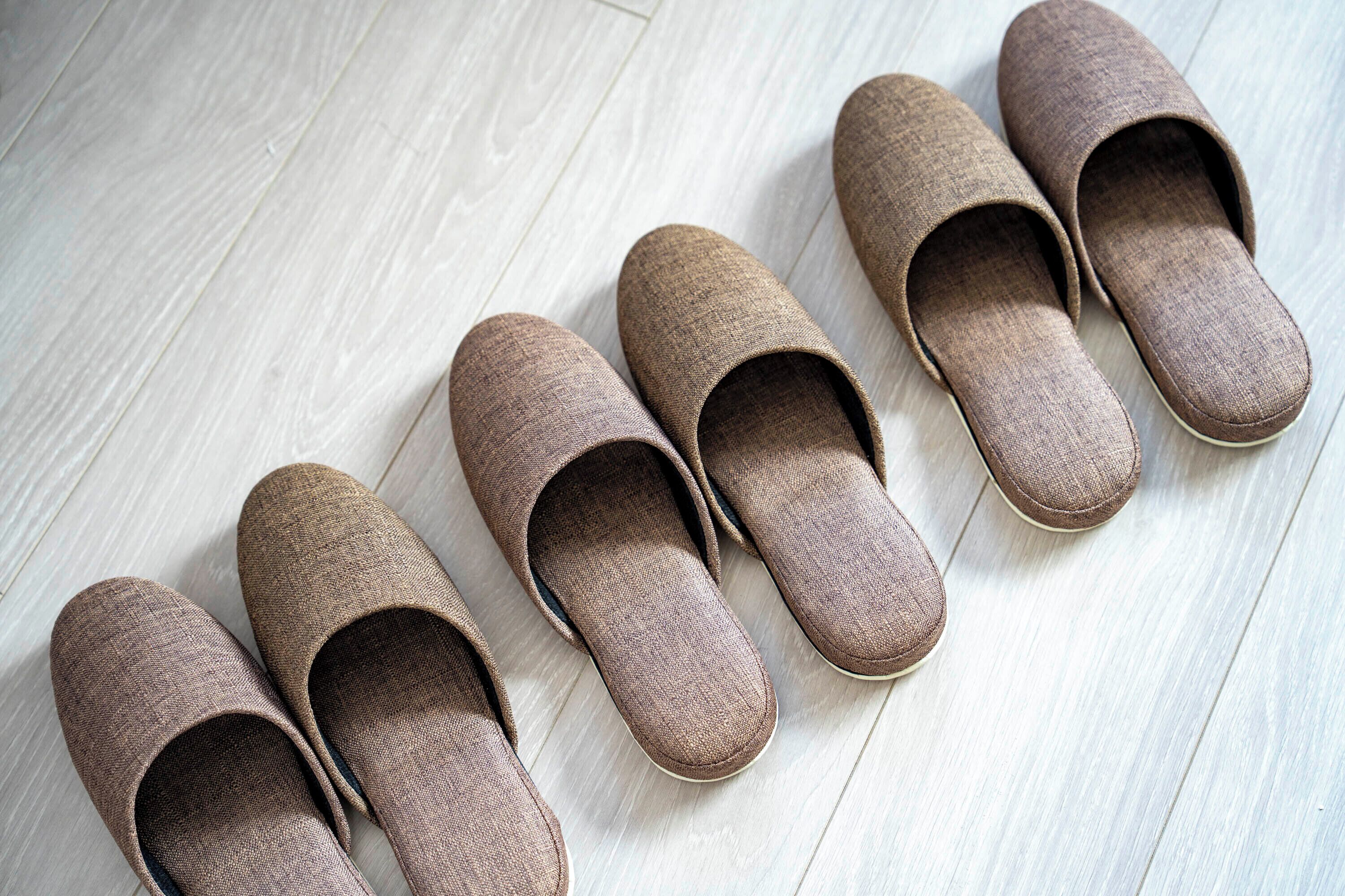 A pair of brown slippers on a light wooden floor.