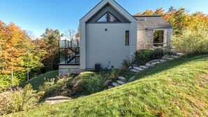 Une maison moderne avec un toit en pente, un petit garage attenant et des fondations en pierre.