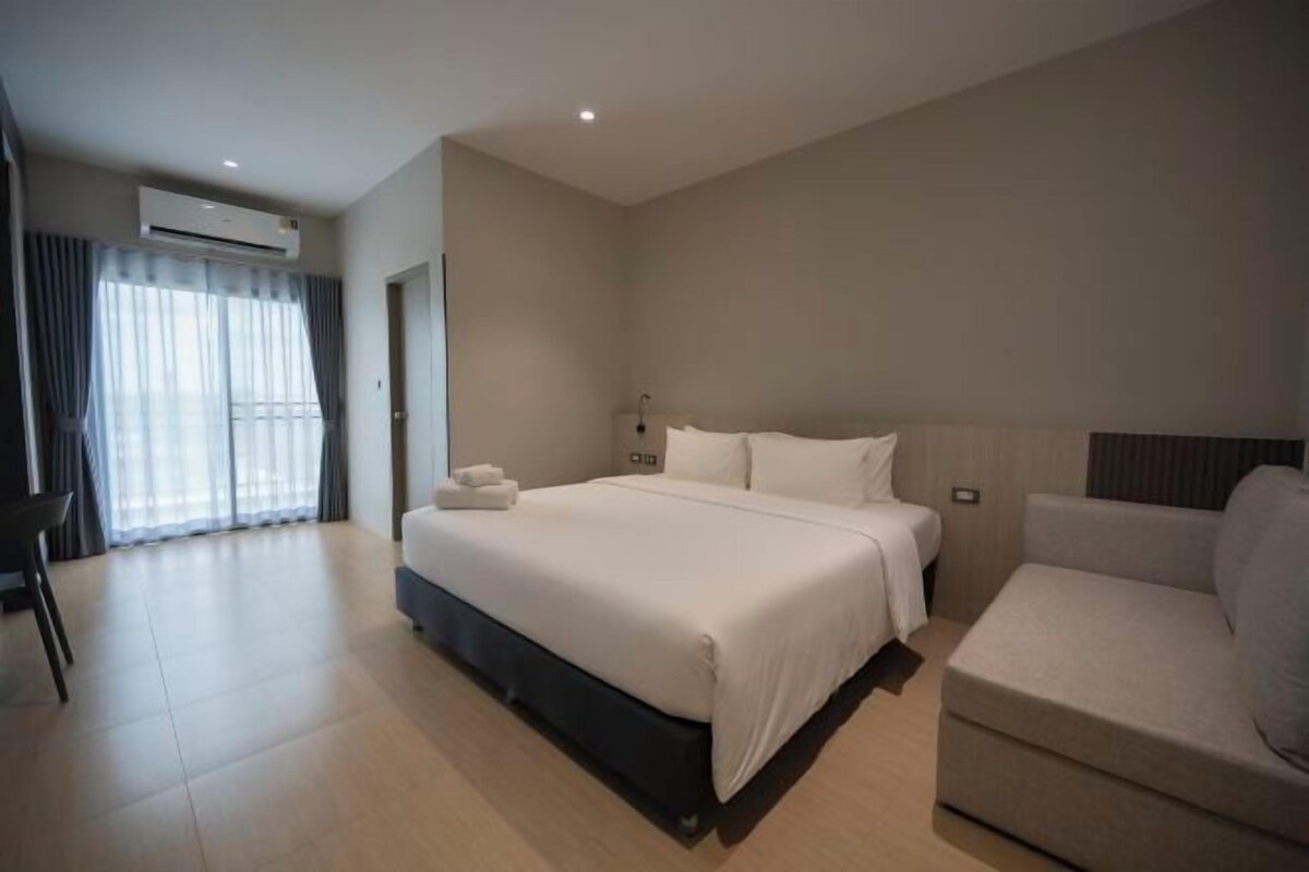 A modern hotel room with a large bed, a sofa, and a desk.