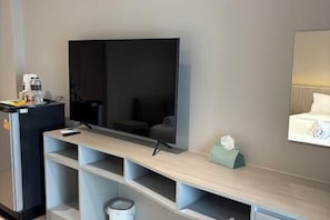 A modern hotel room with a flat-screen TV, a wooden console table, a minibar, and a mirror. - Citywan Ratchaburi (Ratchaburi)