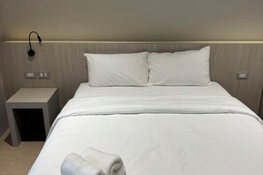 Een hotelkamer met een bed, nachtkastje en een wandlamp.