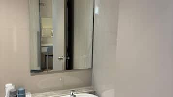 A bathroom with a white sink, a mirror, and a glass shower enclosure.