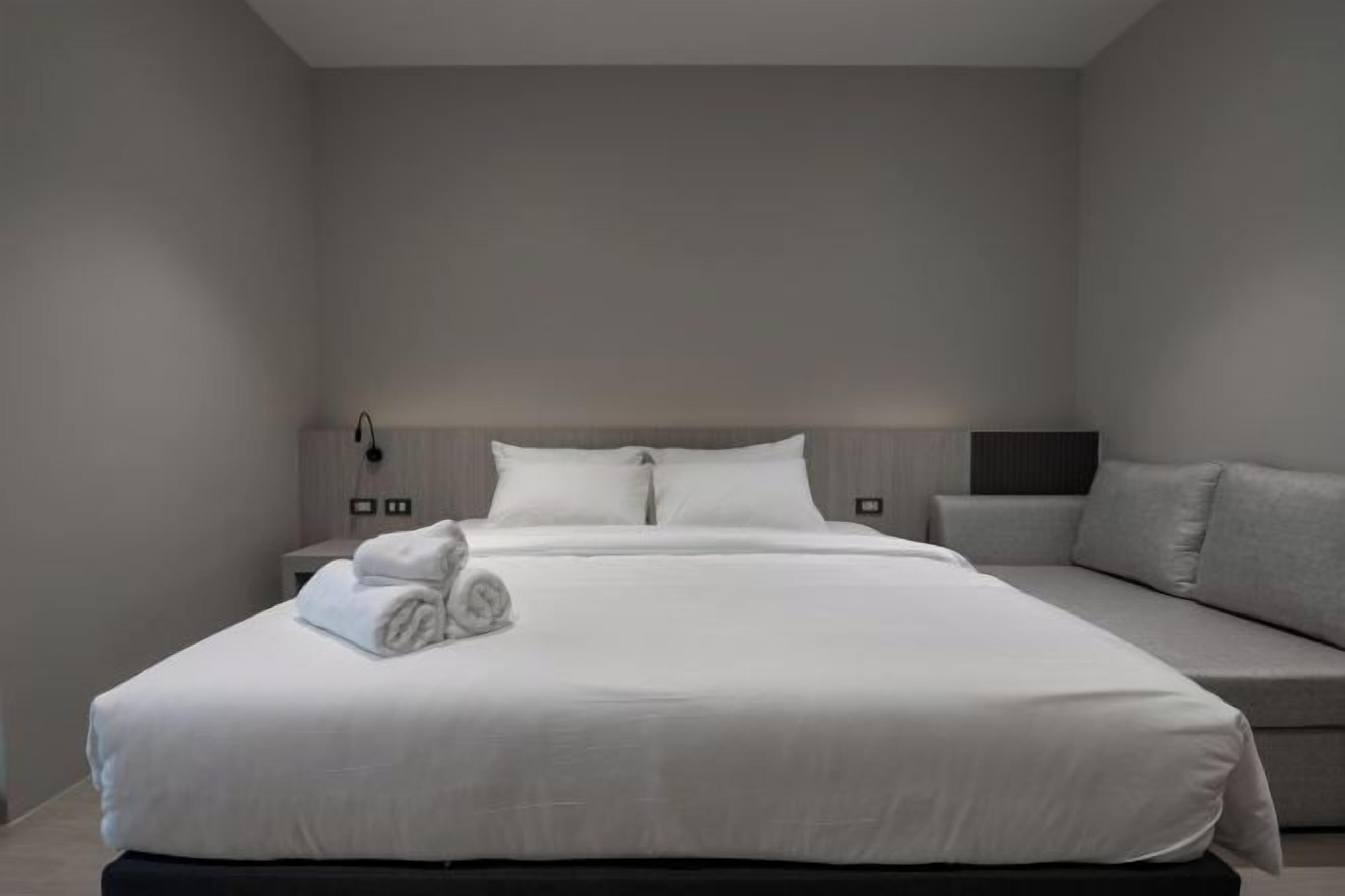Een moderne hotelkamer met een groot bed, een nachtkastje, een lamp en een bank.