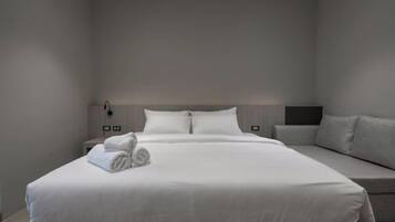 Een moderne hotelkamer met een groot bed, een nachtkastje, een lamp en een bank.