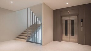 Un interior moderno con una escalera, un ascensor y un diseño limpio y minimalista.