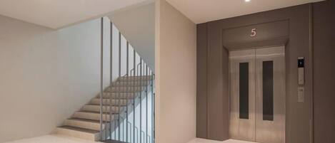 Un interior moderno con una escalera, un ascensor y un diseño limpio y minimalista.
