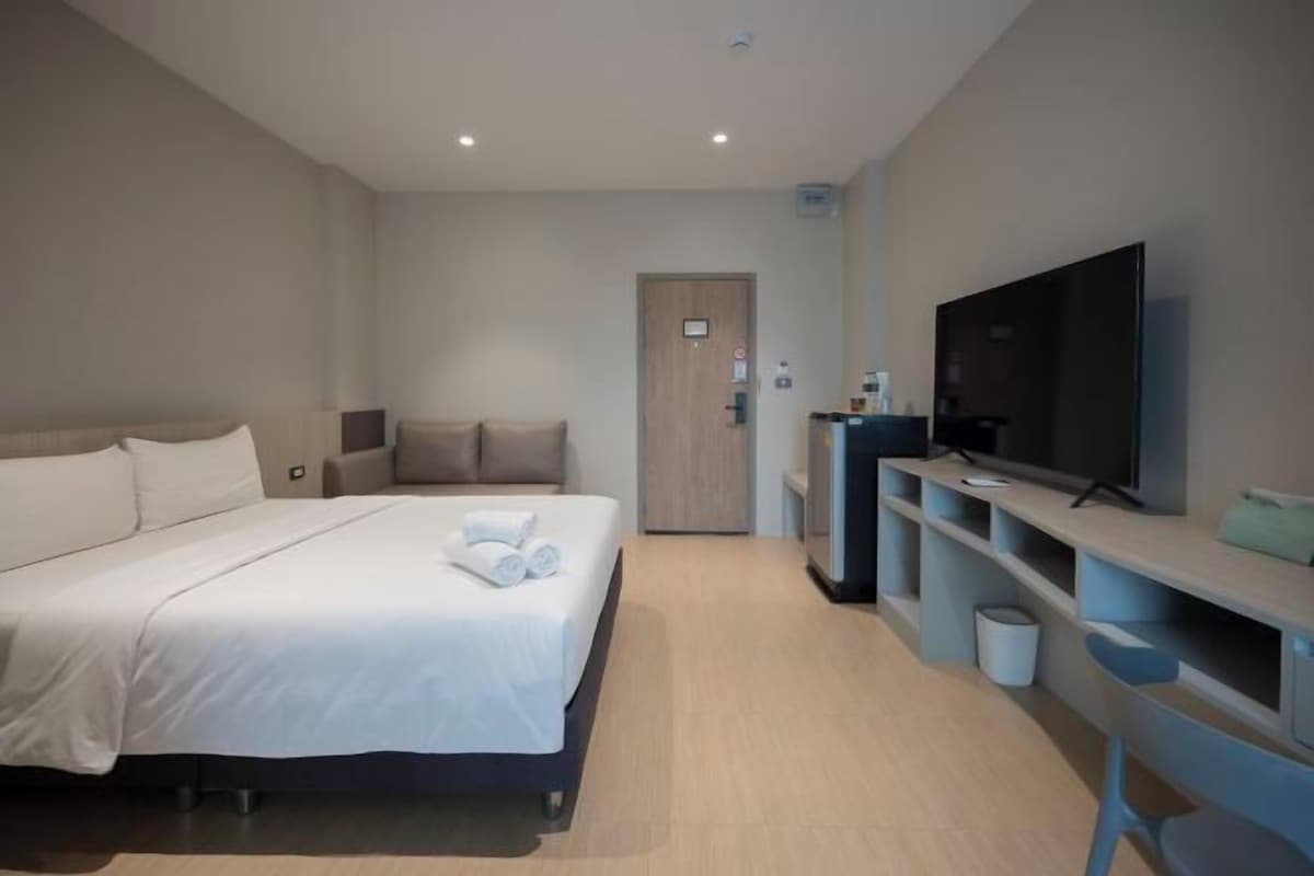 A hotel room with a bed, a television, a desk, and a chair.