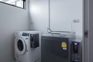 A laundry room with a front-loading washing machine and a stacked dryer.
