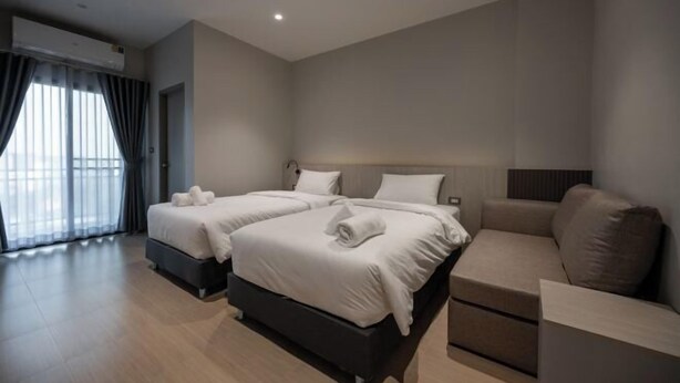 Una habitación de hotel moderna con dos camas, un sofá y un ventanal con cortinas.