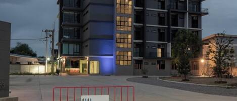 A multi-story hotel building with a modern design, featuring a prominent entrance and a gated driveway.