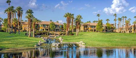 Un resort con varias construcciones, un estanque y palmeras.