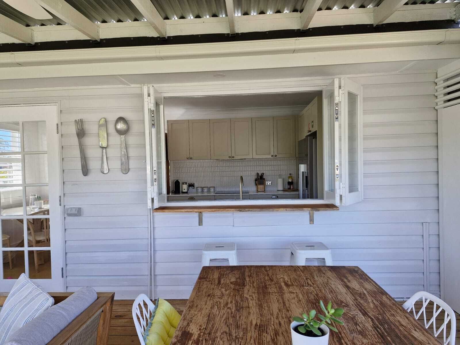 Een compacte keuken met witte kastjes, een houten aanrechtblad en uitzicht op de aangrenzende eetruimte.
