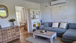 A living room with a grey sofa, wooden coffee table, and a white cabinet. - Caves Beach Coastal Getaway - Perfect for Families (Caves Beach)