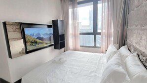 A hotel room with a bed, a mounted TV, and a window with curtains. - 8 Kia Peng Suites Residence by Scape Stay (Kuala Lumpur)