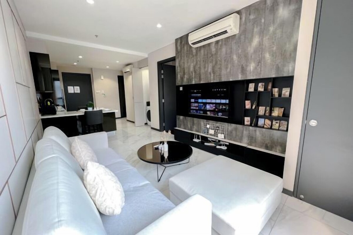 Un salón moderno con un sofá blanco, una mesa de centro y un televisor de pared.