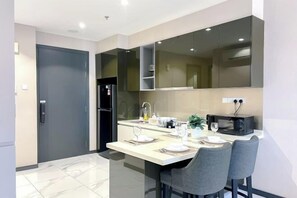 A modern kitchen with a dining area, equipped with a refrigerator, microwave, and a sink. - 8 Kia Peng Suites Residence by Scape Stay (Kuala Lumpur)