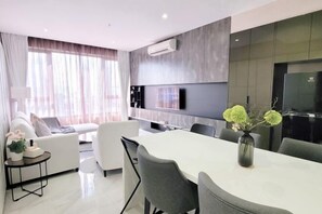 A modern living room with a dining area, a sofa set, a TV mounted on the wall, and a refrigerator. - 8 Kia Peng Suites Residence by Scape Stay (Kuala Lumpur)
