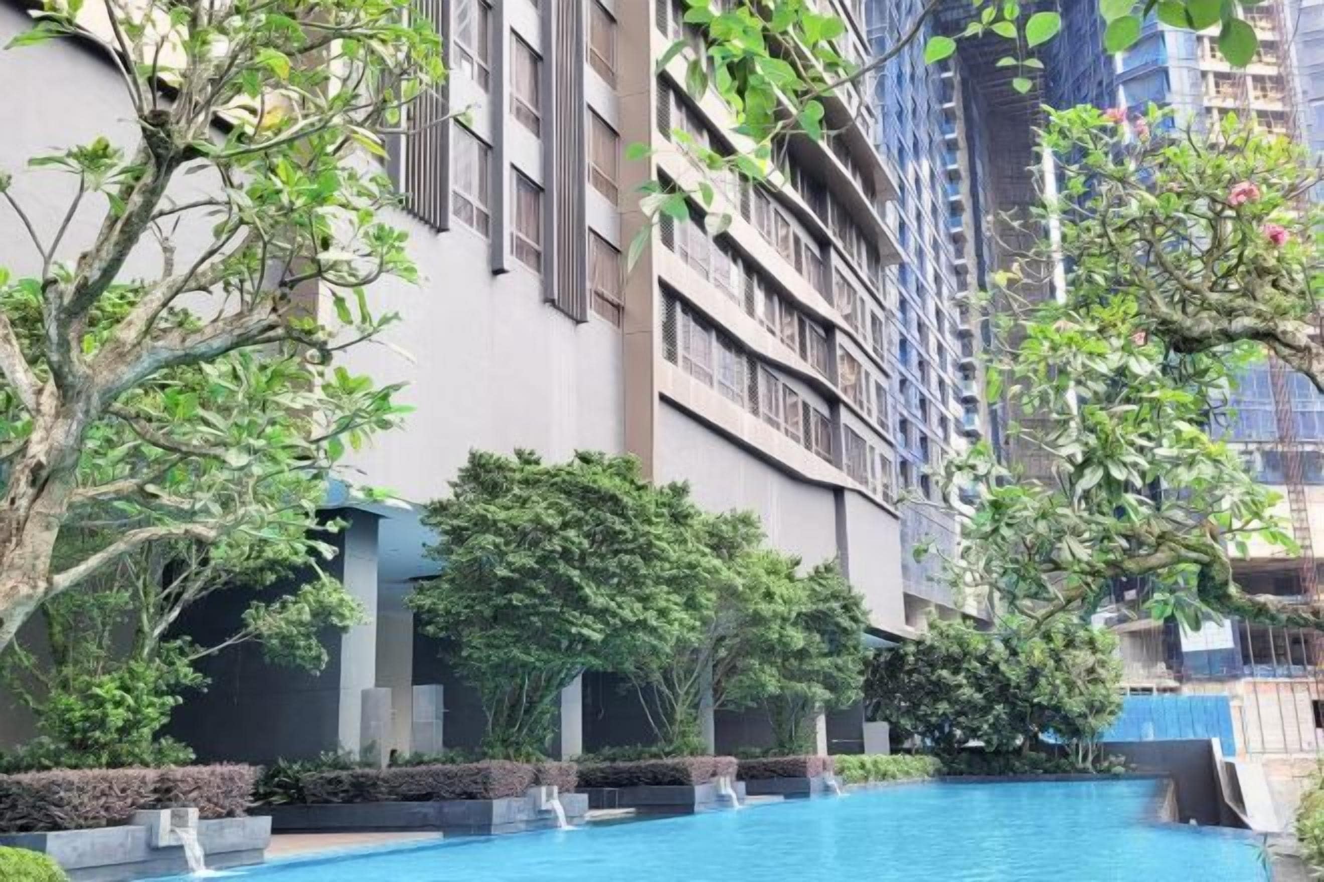 A swimming pool surrounded by greenery and modern buildings.