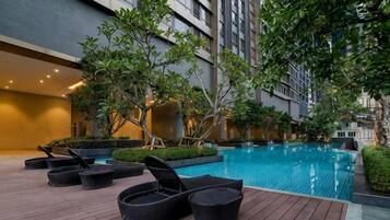 A swimming pool area with lounge chairs and potted plants.