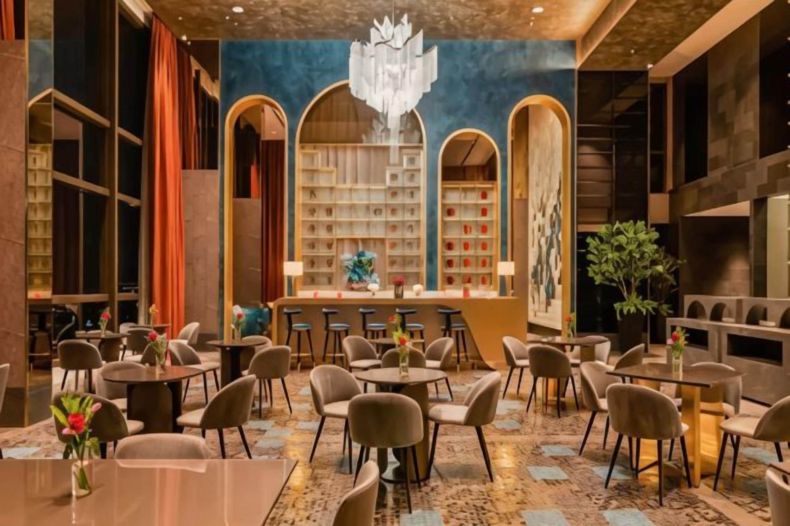 A spacious hotel lobby with multiple seating areas, a central bar, and a large bookshelf.
