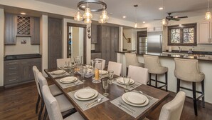 A dining area with a long wooden table set for six, surrounded by six chairs. - New! Hot Tub, Town Center, Western Luxe Delight! (Big Sky)