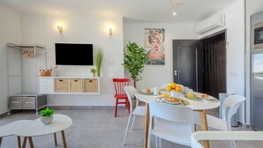Eine moderne Küche mit Essbereich, einem an der Wand befestigten Fernseher und einem Kühlschrank.