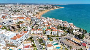 Ein Luftbild einer Küstenstadt mit weißen Gebäuden, einem Strand und einem klaren blauen Meer.