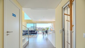 A hallway with a private door, a glass door leading to a balcony, and a view of a cityscape. - Villa Aleksandra - Private Pool (Albufeira)