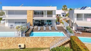 A modern two-story building with a rooftop pool, outdoor seating, and a stone facade. - Villa Aleksandra - Private Pool (Albufeira)