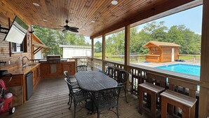 Une terrasse en bois avec une piscine, un espace salon extérieur et un coin barbecue.