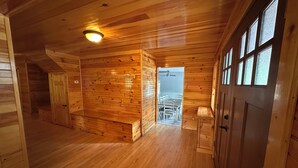 Un intérieur en bois avec un espace repas visible à travers une porte ouverte.