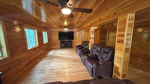 Un intérieur en bois agrémenté d’un ventilateur de plafond, d’un téléviseur à écran plat et de fauteuils inclinables en cuir.
