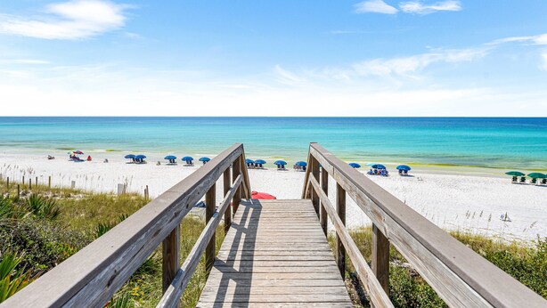 A wooden boardwalk leading to a beach with umbrellas and lounge chairs. - Seagrove Beach Retreat | Steps to the Sand (Seagrove Beach)