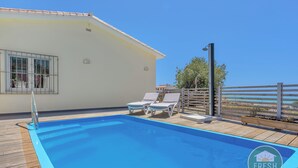 A swimming pool with a wooden deck, two lounge chairs, and a metal railing. - Family cottage in Benajarafe w pool and sea view (Vélez-Málaga)