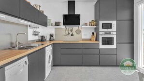 A modern kitchen with grey cabinets, a wooden countertop, a Bosch dishwasher, a built-in oven, and a microwave. - Family cottage in Benajarafe w pool and sea view (Vélez-Málaga)