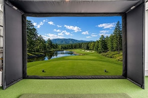A room with a large window displaying a golf course view.