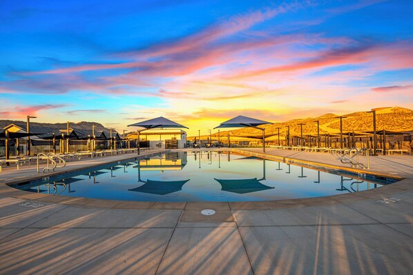 A swimming pool with a clear view of the surrounding area, including a covered seating area and a desert landscape in the background.