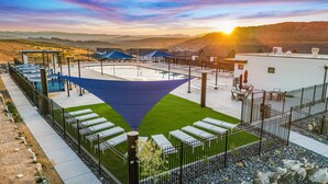 A rooftop pool area with a blue shade sail, outdoor seating, and a view of the surrounding landscape. - 1626, Private Swim Spa, Hot tub, Resort access (Washington)