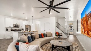 A modern living room with a sectional sofa, a round coffee table, and a ceiling fan. - 1626, Private Swim Spa, Hot tub, Resort access (Washington)