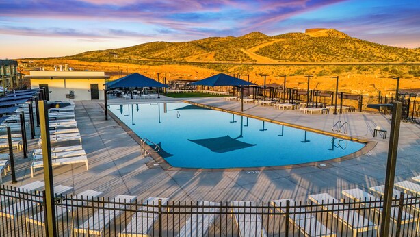 A pool area with lounge chairs and umbrellas, surrounded by a fence, with a desert landscape in the background. - 1626, Private Swim Spa, Hot tub, Resort access (Washington)