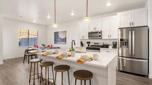 A modern kitchen with white cabinets, stainless steel appliances, and a central island with stools. - 1626, Private Swim Spa, Hot tub, Resort access (Washington)